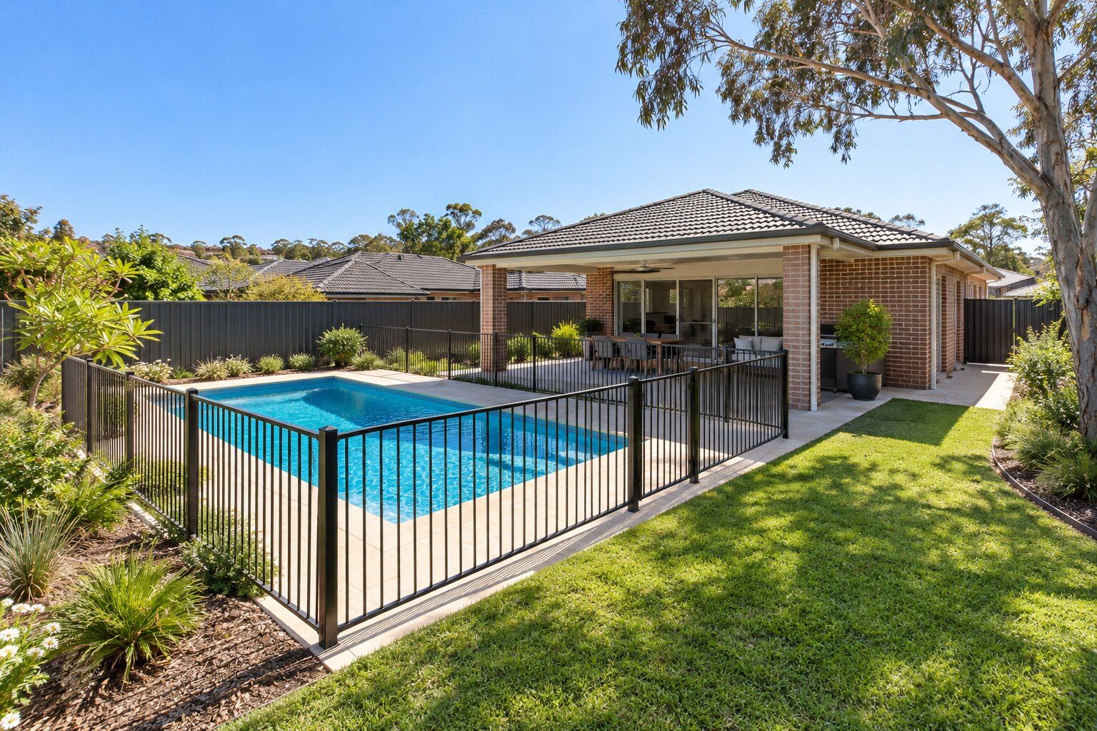 Pool safety in Sydney: brick home with a fenced in-ground pool and a covered outdoor area